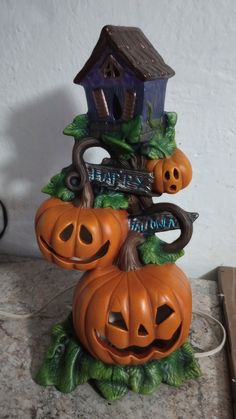 three pumpkins stacked on top of each other in front of a house with a birdhouse