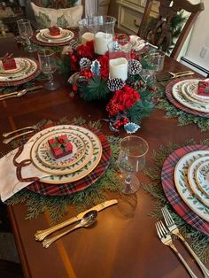 the table is set for christmas dinner with red and green napkins, silverware