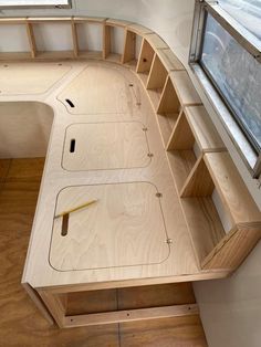 a wooden desk with shelves and a window in the back ground, next to a wood floor