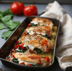 a pan filled with chicken and spinach covered in cheese on top of a table