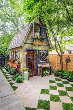 a small garden shed with potted plants on the outside and a picnic table in front