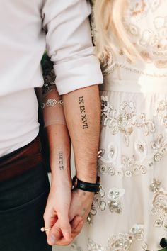 two people holding hands with tattoos on their arms