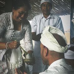 a woman is handing something to a man who is wearing a white turban