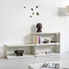 a white shelf with books and figurines sitting on top of it next to a lamp