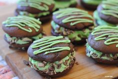 chocolate cookies with green frosting on a wooden cutting board