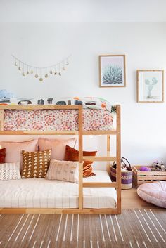 a bunk bed with pink and gold pillows in a room filled with pictures, rugs and other items