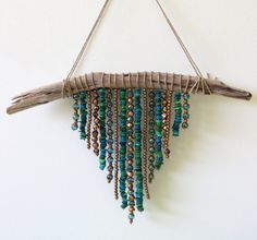 a piece of driftwood with beads hanging from it's side on a wall