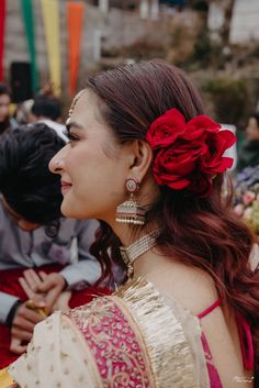 a woman with red flowers in her hair is looking at another woman's face