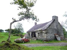 an old house with a car parked in front of it on the side of a road