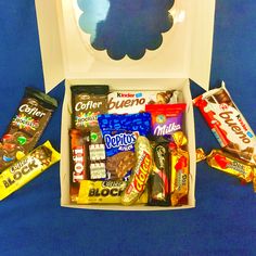 an open box filled with candy and candies on a blue tableclothed surface