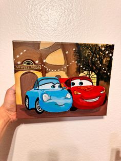 a person holding up a painting of cars