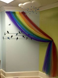 there is a rainbow curtain with birds on it in the corner of this room,