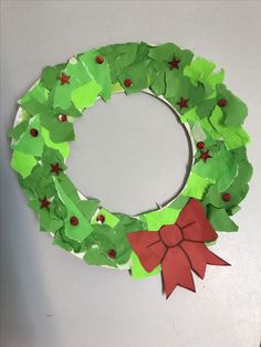 a wreath made out of green paper with a red bow on the front and bottom