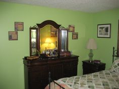 a bedroom with green walls and wooden furniture