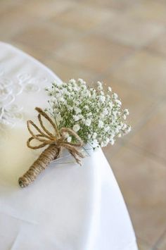 a bouquet of baby's breath sits on top of a white cloth covered table