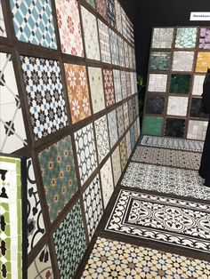 a woman standing in front of a wall covered with tiles and flooring designs,