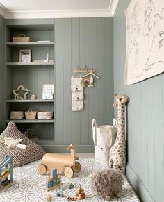 a baby's room with toys and bookshelves on the wall, including stuffed giraffes