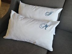 two white pillows sitting on top of a gray couch