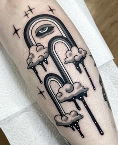 a black and white tattoo design on the leg of a person with clouds, stars and an eye