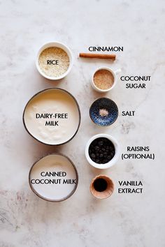 ingredients to make an ice cream smoothie laid out on a marble counter top, including cinnamon, sugar, coconut milk, and cocoa