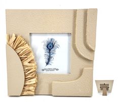 a white photo frame with a blue peacock feather