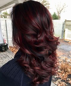 the back of a woman's head with dark red hair and long wavy curls