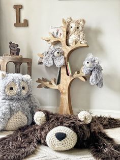 two stuffed animals sitting next to each other in front of a tree with owls on it