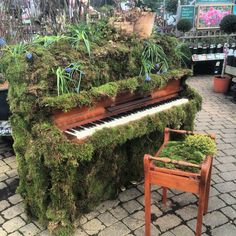 an old piano is covered in moss and has been turned into a planter with plants growing on it