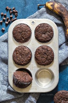 a muffin tray with six chocolate cupcakes and a banana on the side