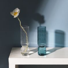 two vases sitting on a table with a single flower in one and the other