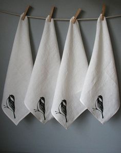 three towels hanging on a clothes line with black and white embroidered bird designs in the middle