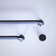 two black handles on a white surface and one has a round knob in the middle