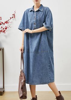 a woman in a denim dress holding a handbag and looking off to the side