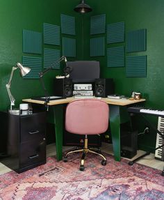 a room with green walls and a pink chair in front of a desk that has speakers on it