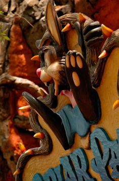 a close up of a wooden sign with animals on it's face and hands