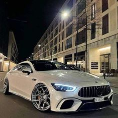 a white mercedes cla parked on the side of a street in front of tall buildings