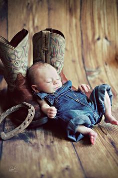 a baby laying on top of a pair of cowboy boots