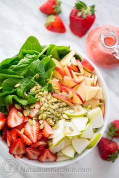 a white bowl filled with lots of fruit and veggies on top of a table