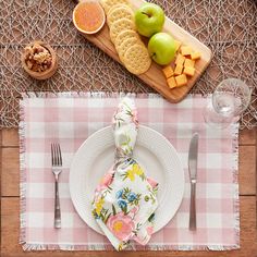 a place setting with flowers and fruit on the table