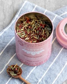 a pink cup filled with lots of tea next to a wooden spoon on top of a towel