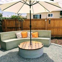 an outdoor seating area with umbrella and wooden table in the middle, surrounded by gravel