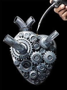 a heart shaped machine with gears attached to it's sides, being held by a hand