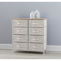 two vases are sitting on top of a white chest of drawers in a room