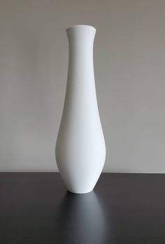 a white vase sitting on top of a black table