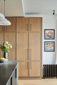 a kitchen with wooden cabinets and flowers in a vase on the counter next to an radiator