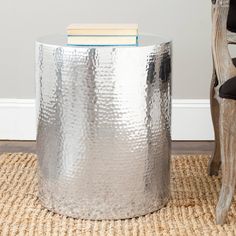 a silver metal stool with a book on top and a rug in front of it