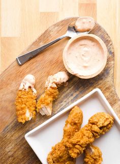 fried chicken on a plate with dipping sauce next to it and a spoon in the bowl