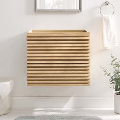 a wooden slatted window in a bathroom next to a white rug and potted plant