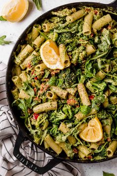 a skillet filled with pasta and broccoli on top of a white table