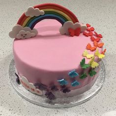 a pink cake decorated with rainbows and clouds